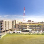 施設周辺の都市風景。公園と建物群が見える明るい昼間の景観